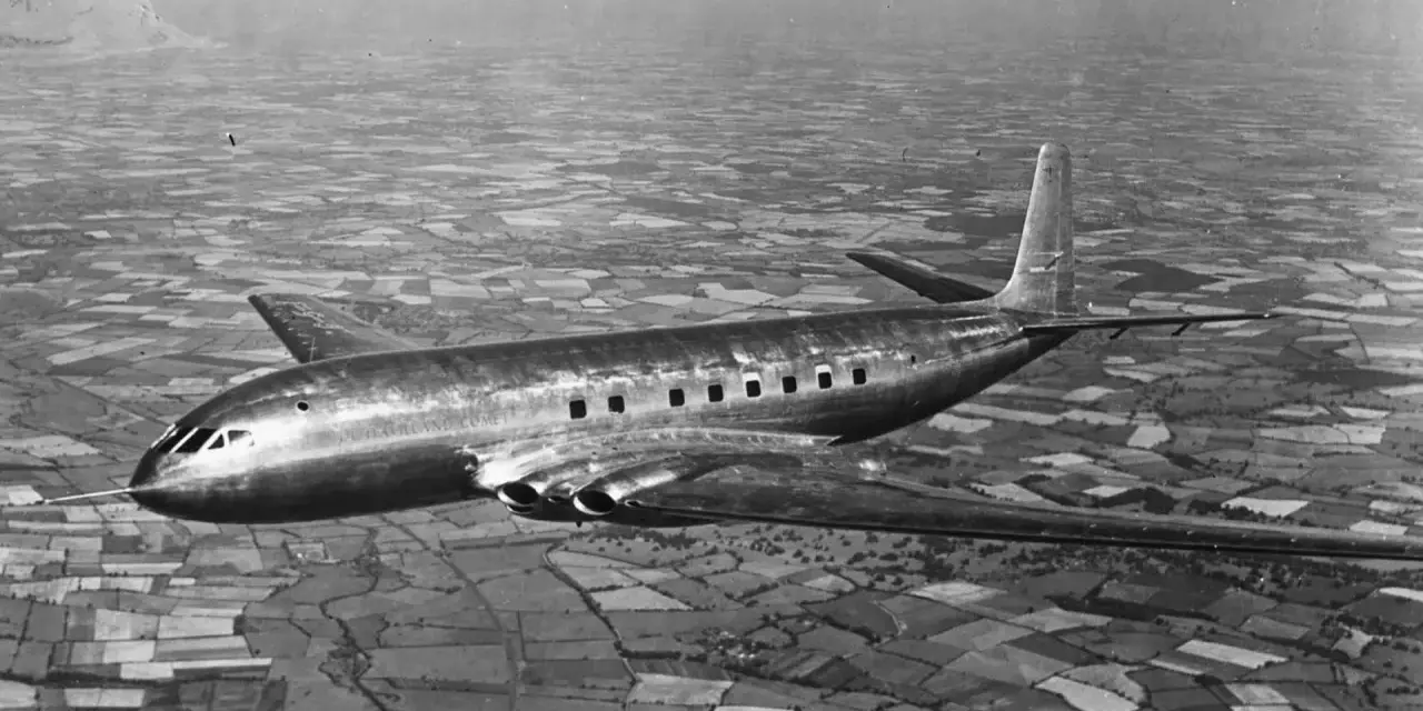 Pierwszy samolot pasażerski, lśniący de Havilland Comet, przelatuje nad patchworkiem pól.