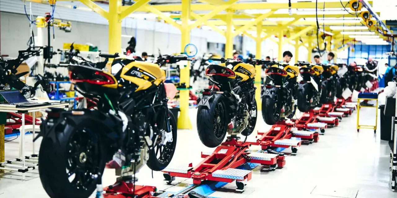 Linea di produzione MV Agusta: moto sportive gialle e nere in fase di assemblaggio su supporti rossi.