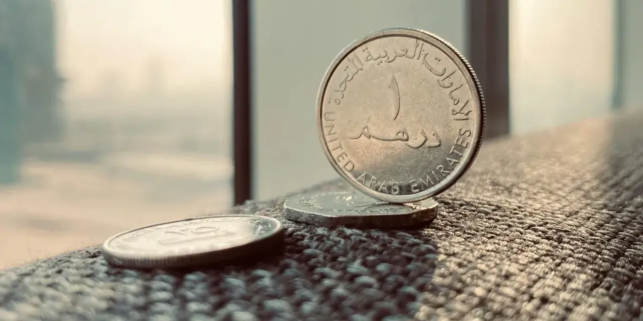 Monety z Zjednoczonych Emiratów Arabskich. Jedna z nich, z napisem "United Arab Emirates", stoi pionowo. To właśnie te monety symbolizują walutę AED, co to jest?