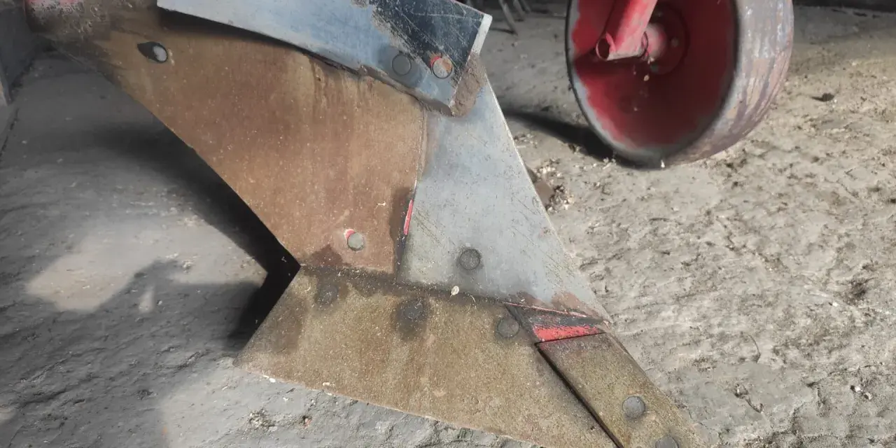 Metalowy lemiesz pługa, gotowy do pracy na polu. To właśnie on odwraca ziemię, przygotowując ją pod zasiew.
