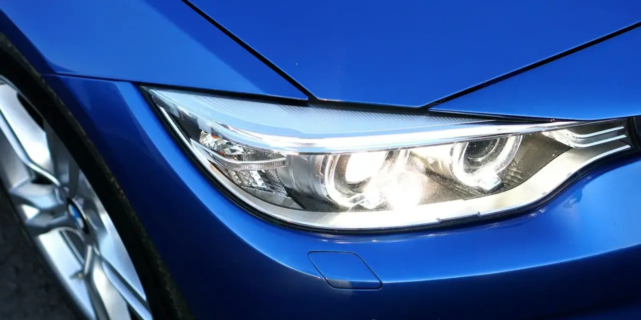 Blå BMW med strålkastare och fälg. En ren bil som väntar på att bli tvättad med en tvätthandske.
