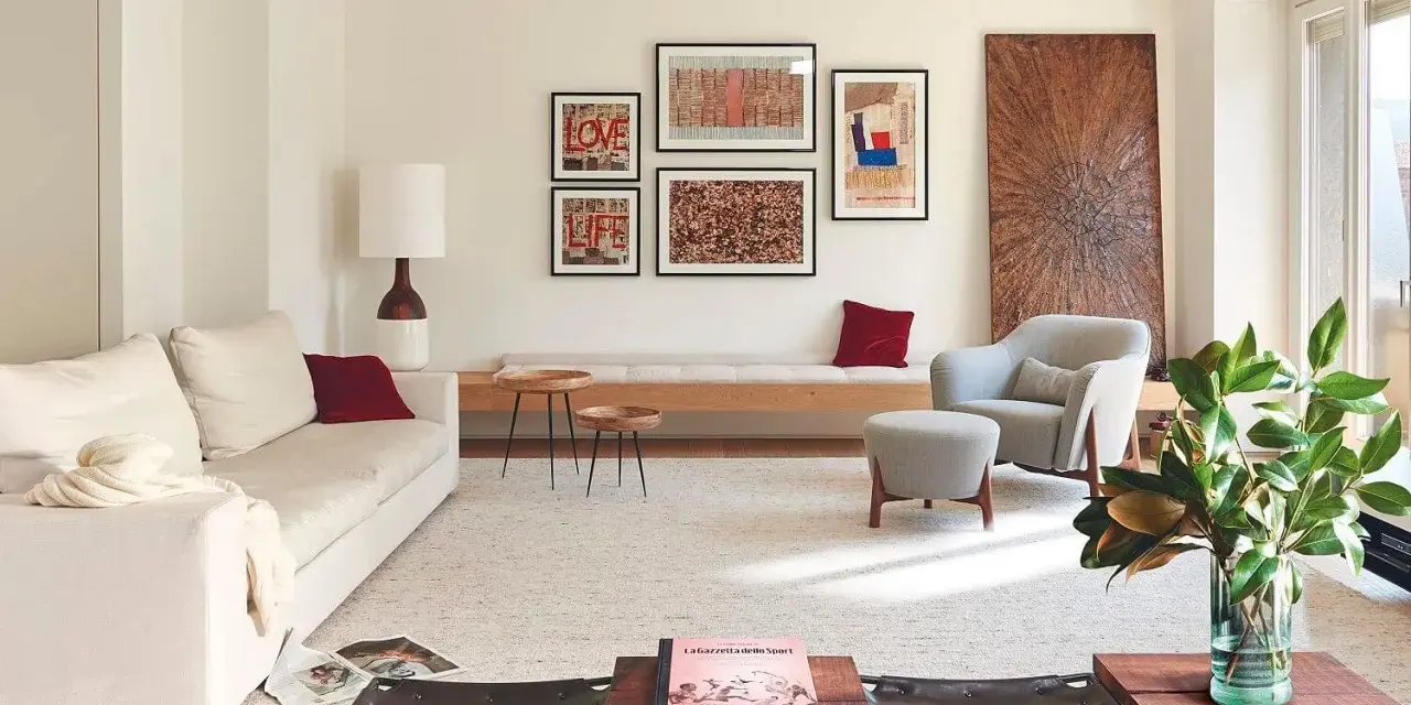 Una composición de cuadros en la pared, con arte abstracto y tipografía, decora este salón moderno junto a un sofá blanco y una butaca gris.