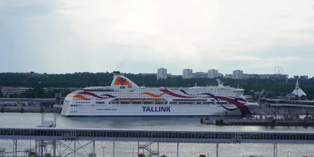 Prom Tallink płynie z Tallinna do Sztokholmu. Statek z kolorowymi pasami na burcie cumuje w porcie.