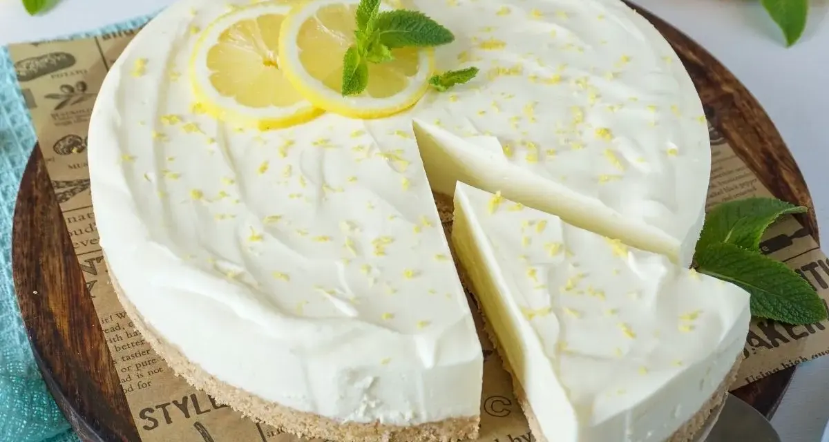 Cremige Philadelphia Torte mit Zitronenscheiben und Minze, ein Stück wurde bereits entnommen.