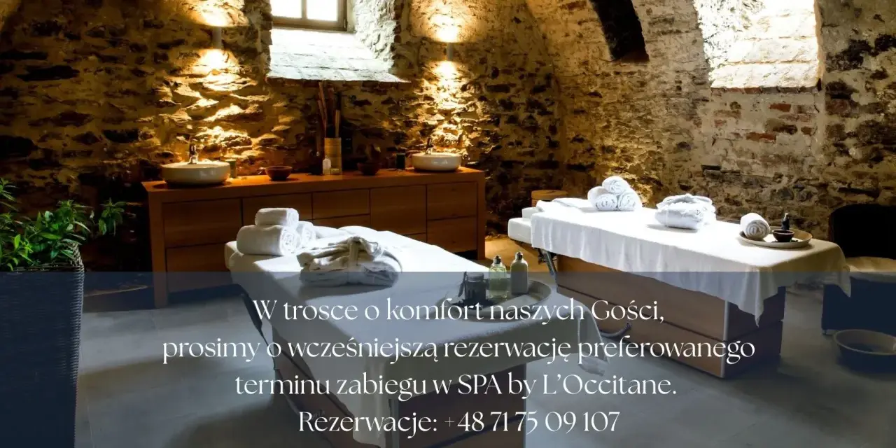 Przytulne wnętrze SPA koło Wrocławia z dwoma stołami do masażu, kamiennymi ścianami i relaksującym oświetleniem.
