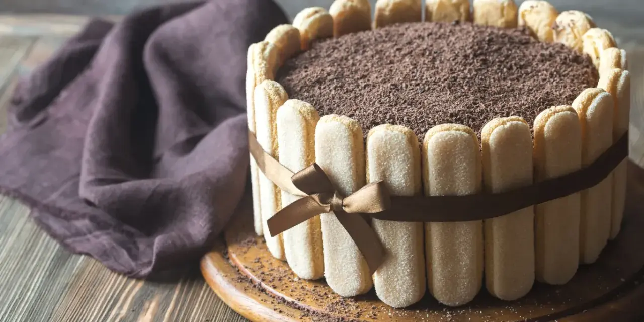 Wykwintny tort tiramisu, otoczony biszkoptami i ozdobiony czekoladową posypką, prezentuje się apetycznie.