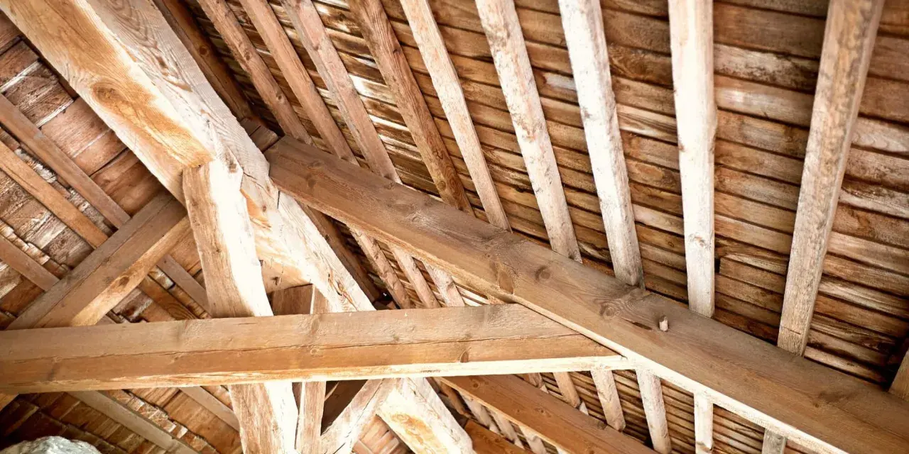 Vue rapprochée d'une charpente ancienne en bois, témoignant d'un savoir-faire artisanal. Un futur projet de traiter charpente pour la préserver.