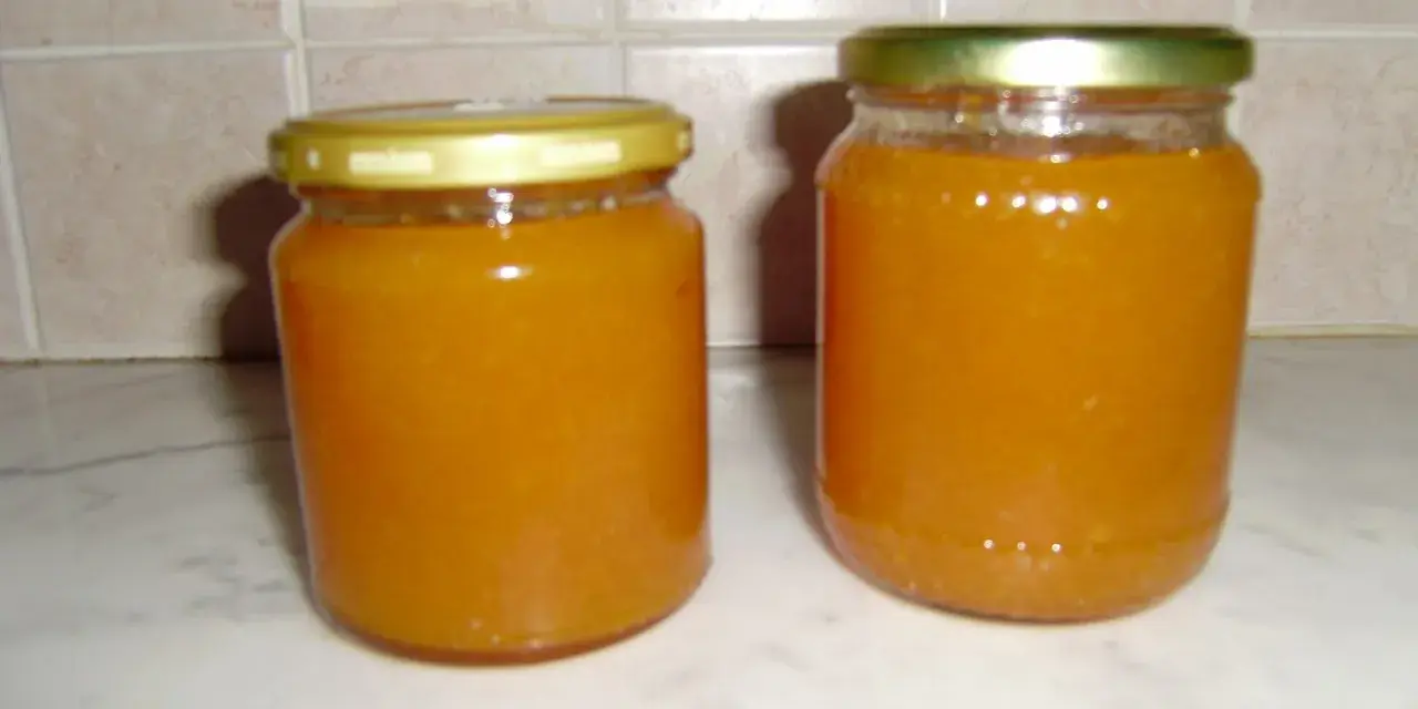 Due barattoli di marmellata di pesche fatti in casa, pronti per essere gustati.