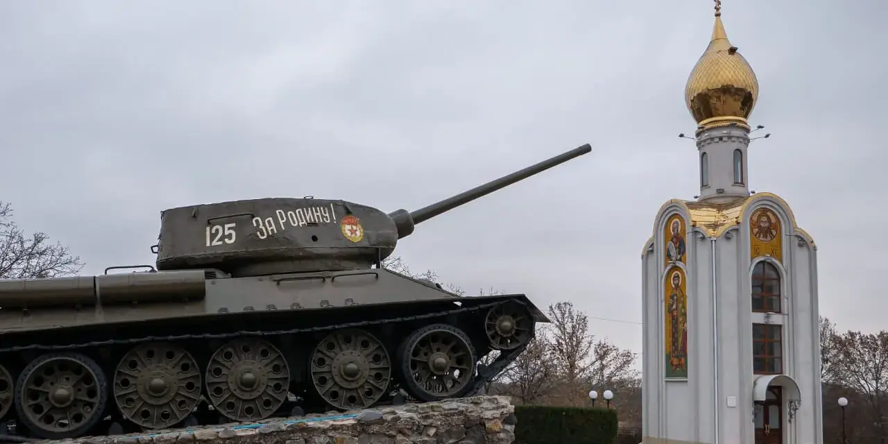 Czołg z napisem "Za Rodinu!" stoi obok cerkwi z złotą kopułą. Pomnik na nadniestrze.