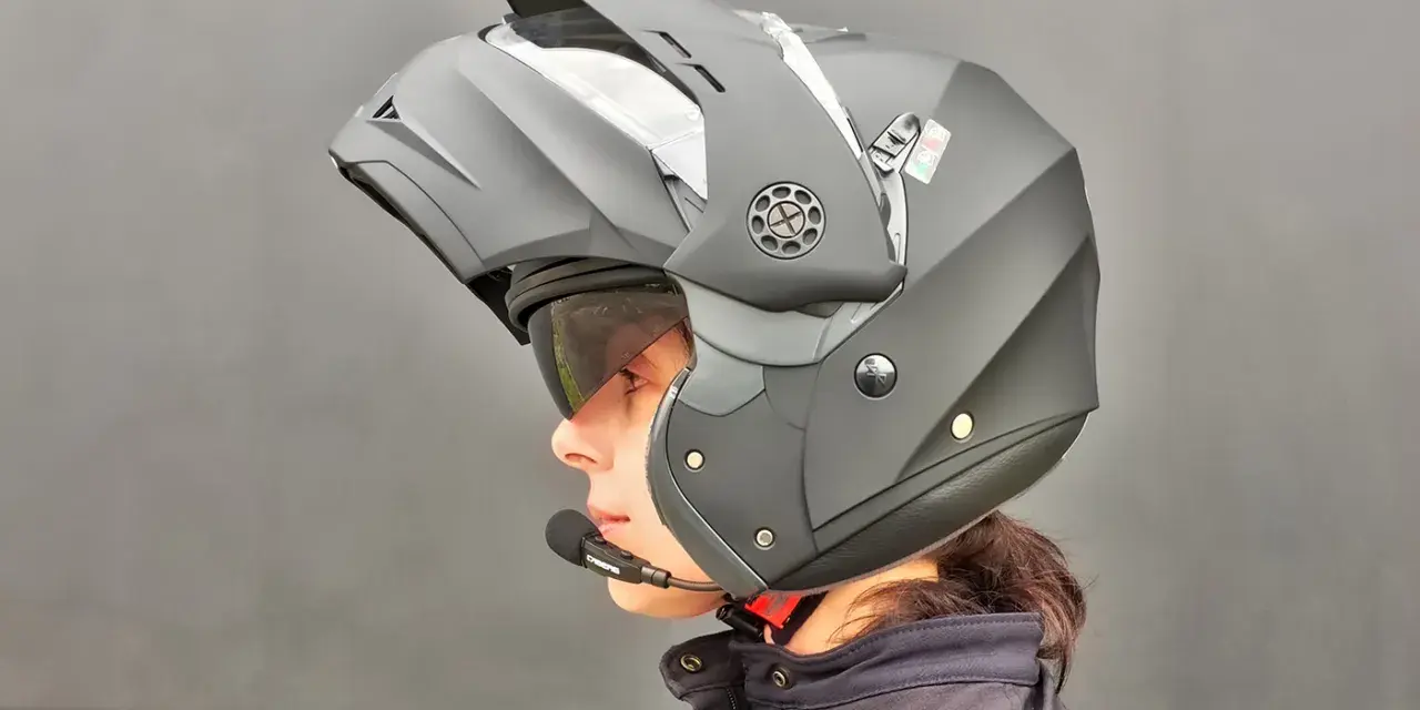Profilo di una persona con casco da moto modulare nero, visiera sollevata e microfono. Guida sicura: come scegliere casco moto.