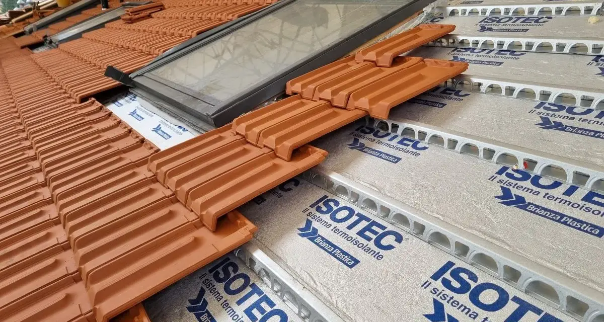 Tegole in laterizio su un tetto in costruzione, con lucernario e isolamento termoisolante ISOTEC.