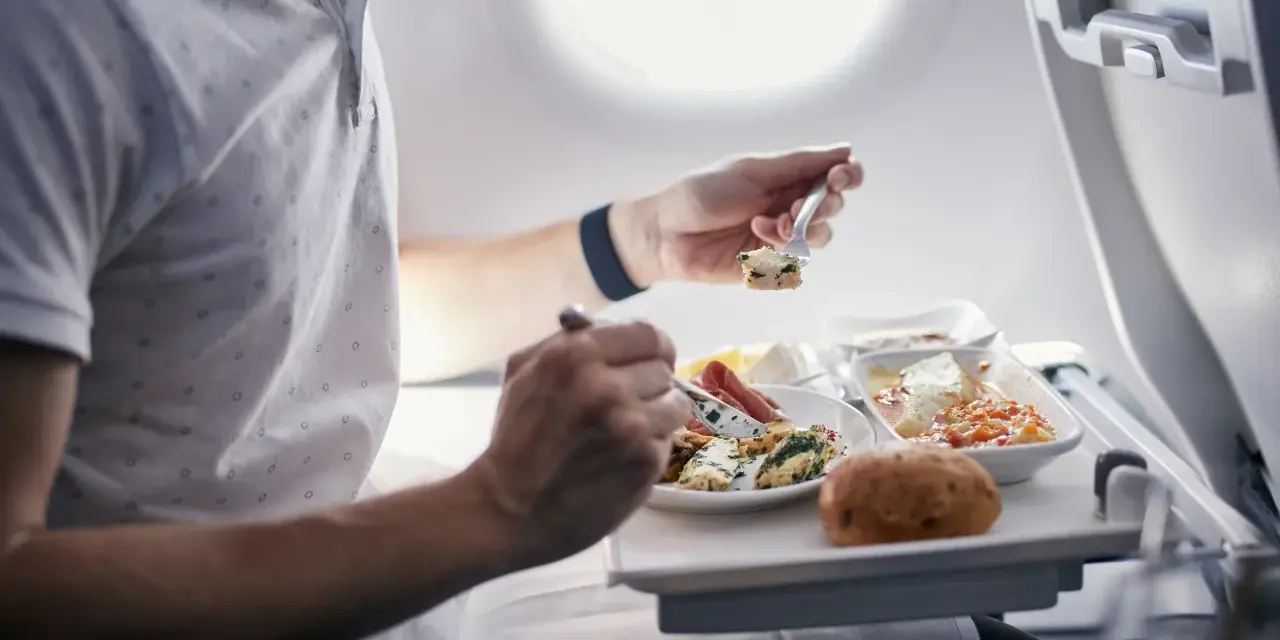 Pasażer je posiłek na pokładzie samolotu. Zastanawiasz się, czy można przewozić jedzenie w bagażu rejestrowanym Ryanair?