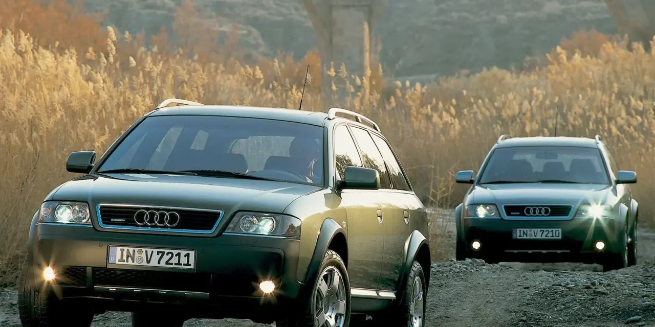 Dwa Audi A6 C5 2.5 TDI Allroad jadące po kamienistej drodze, w tle łuk mostu i suche trawy.