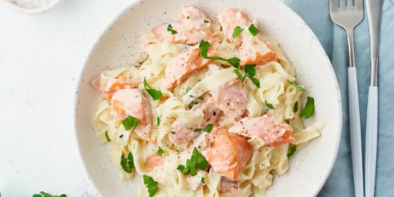 Pasta cremosa con trozos de salmón rosado y perejil fresco. Un plato delicioso y nutritivo.