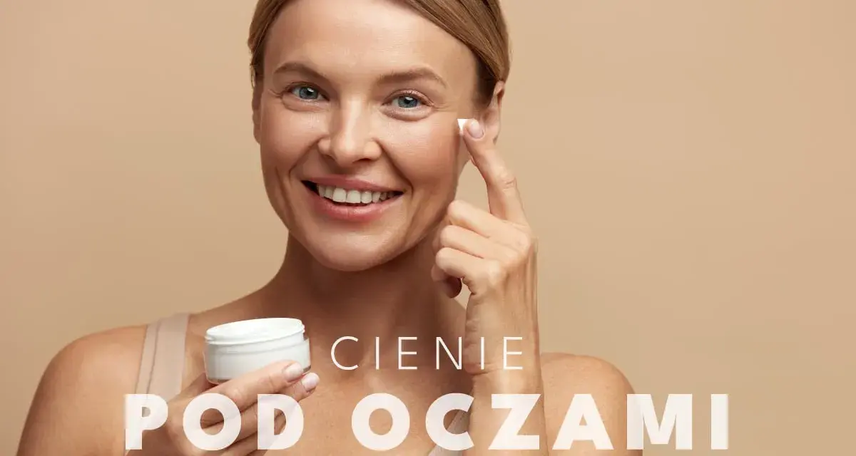 Uśmiechnięta kobieta aplikuje krem pod oczy. To rozwiązanie na cienie pod oczami, które przywróci blask Twojej skórze.