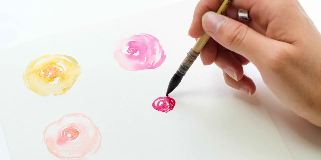 Une main peint des fleurs à l'aquarelle. Un bouquet de fleurs peinture facile, avec des touches de rose, jaune et pêche.