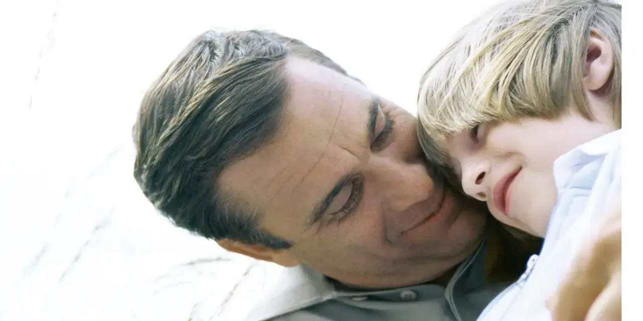 Vater und Kind kuscheln. Auch bei getrennt lebenden Eltern ist die Haftpflichtversicherung wichtig für den Nachwuchs.