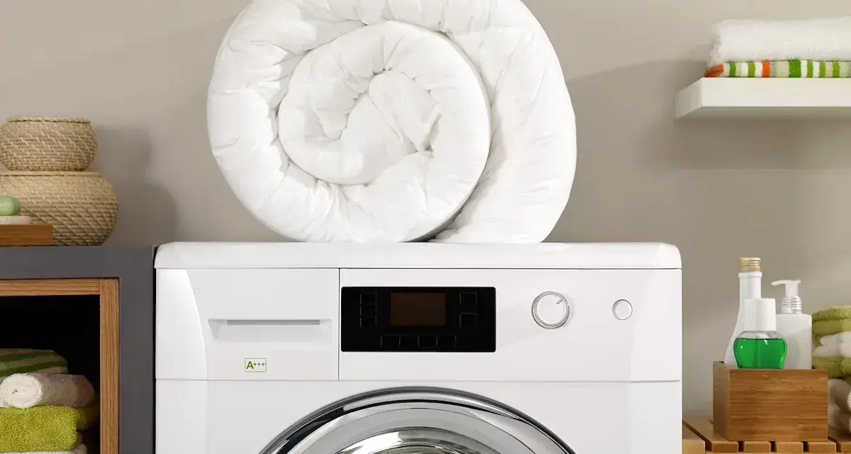 Piumone bianco arrotolato sopra una lavatrice. Pronto per essere lavato in lavatrice a 40 gradi per un bucato fresco e pulito.
