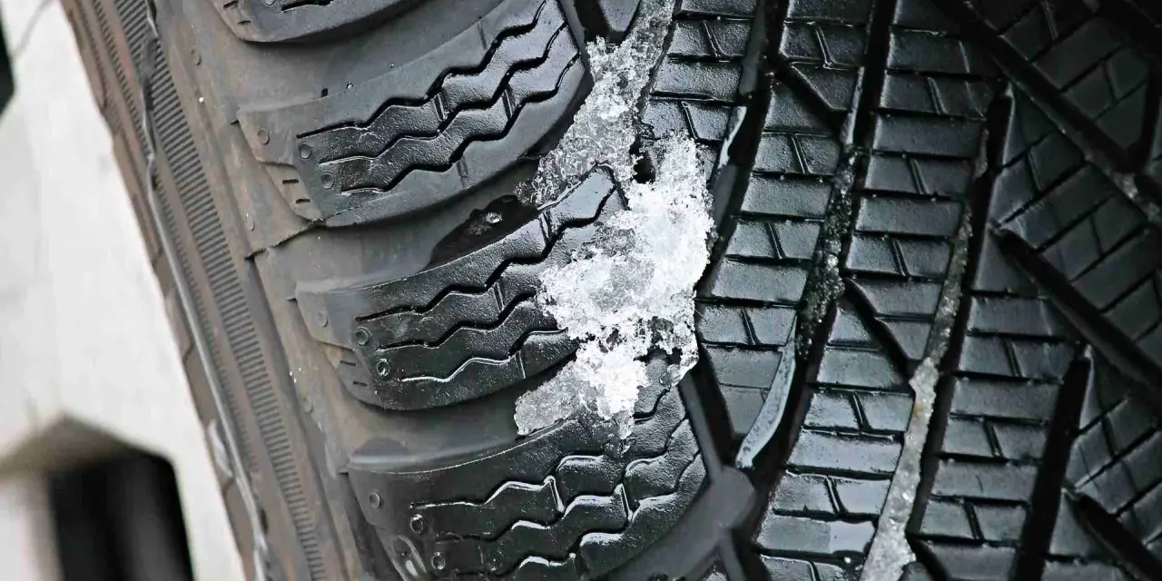 Gomme invernali con neve e ghiaccio incastrati nel battistrada. Le gomme screpolate battistrada mostrano segni di usura, ma ancora funzionali.