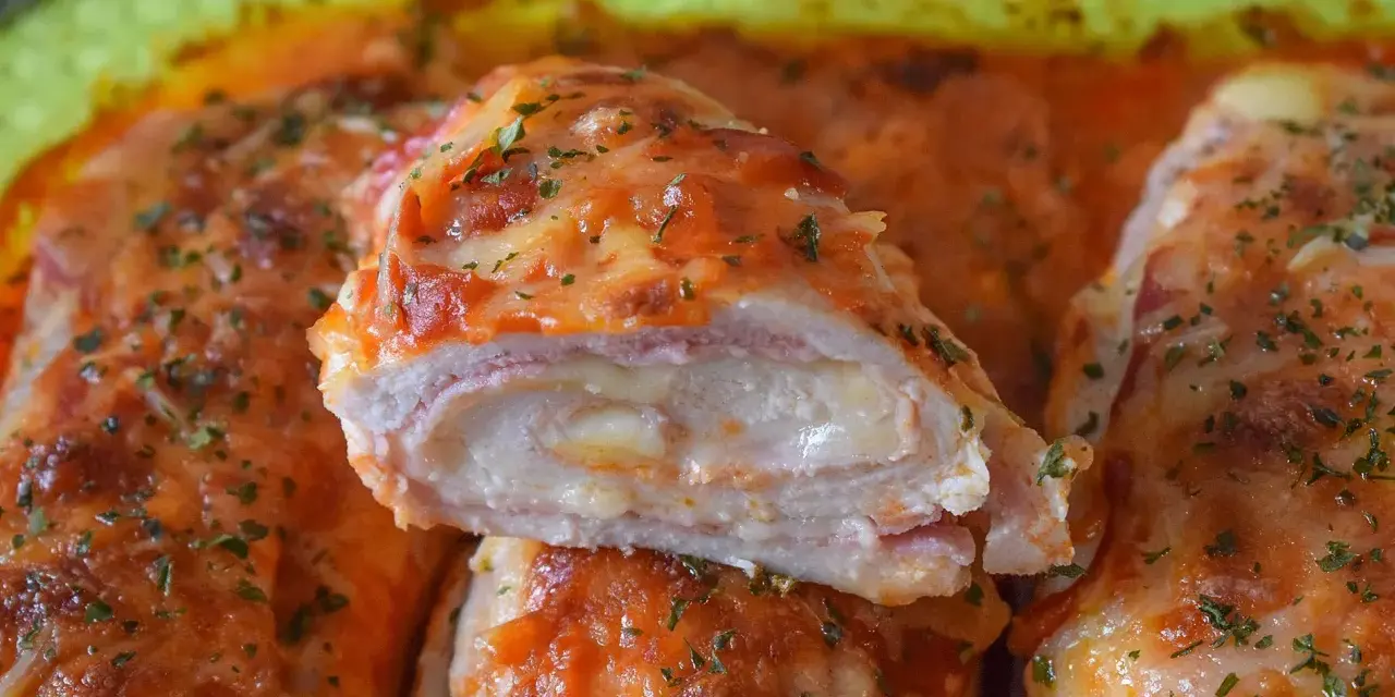 Pechugas de pollo rellenas de queso y jamón, cubiertas con salsa de tomate y queso gratinado, espolvoreadas con perejil fresco.