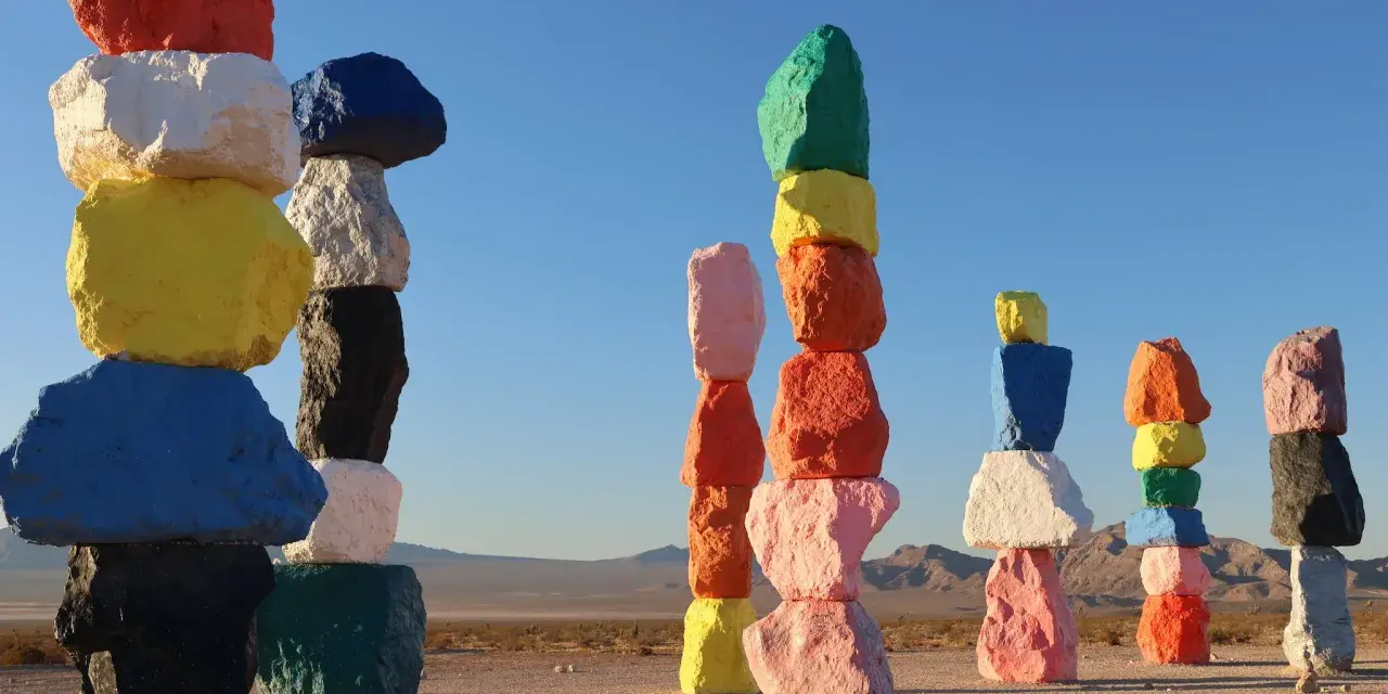 Les **seven magic mountains** illuminent le désert. Des rochers colorés empilés créent une œuvre d'art vibrante sous un ciel bleu.