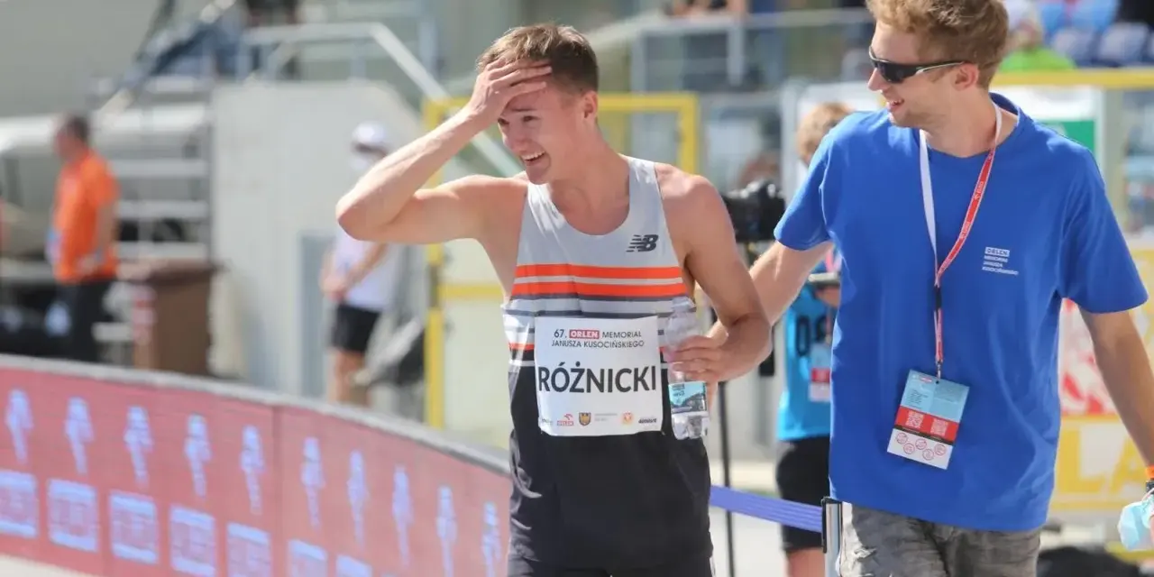 Krzysztof Różnicki, lekkoatleta, po biegu z dłonią na czole, obok niego stoi mężczyzna w niebieskiej koszulce.