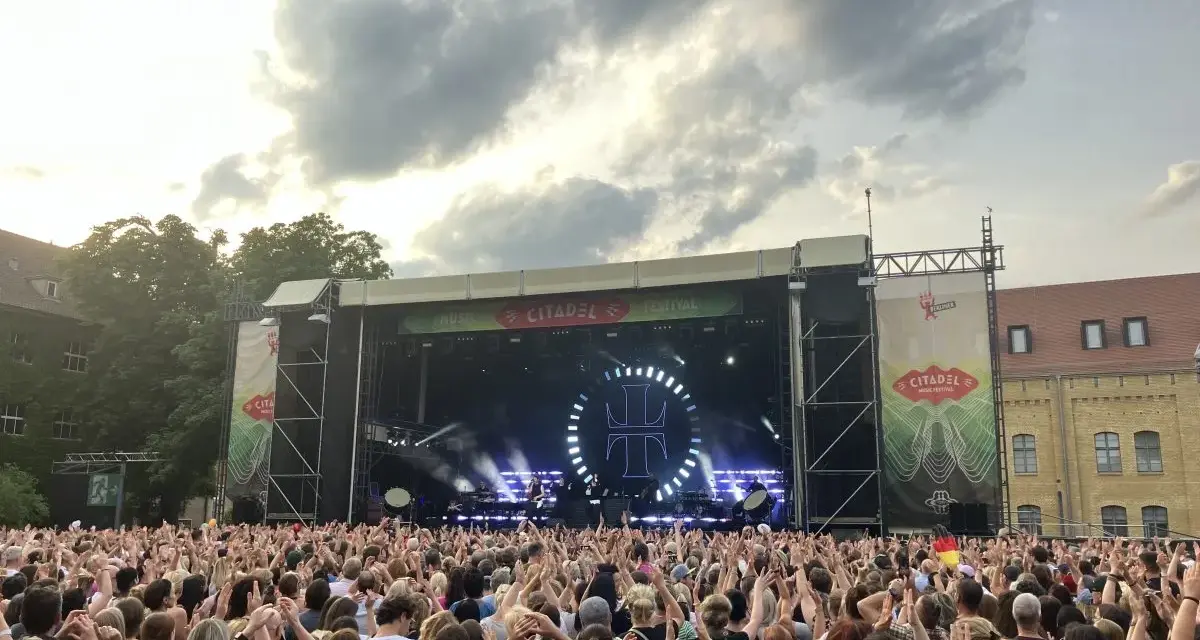 Ein riesiges Publikum feiert beim Citadel Music Festival in Berlin. Die Bühne ist beleuchtet, die Menge jubelt.