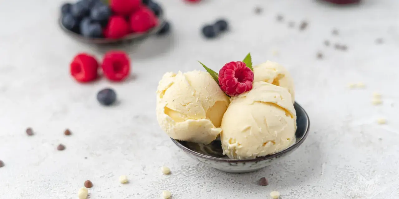 Cremiges Vanilleeis, garniert mit einer Himbeere. Perfekt, um eis ohne zucker selber machen zu lernen.