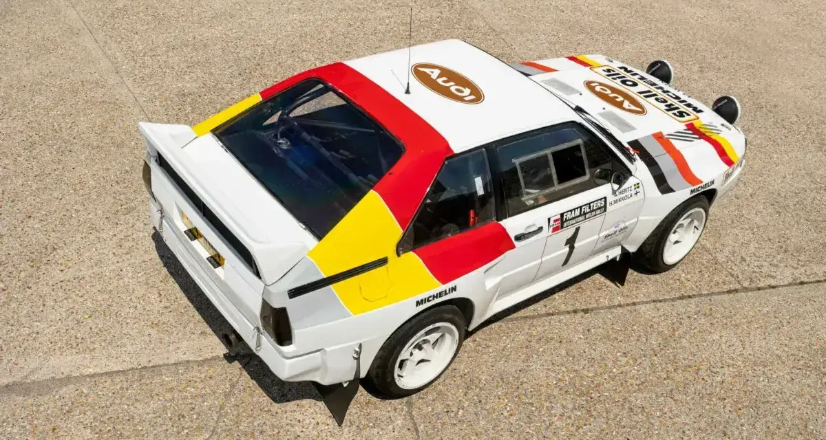 Biały rajdowy **Audi quattro S1** z kolorowymi pasami i logotypami sponsorów, gotowy do podboju szutrowych tras.