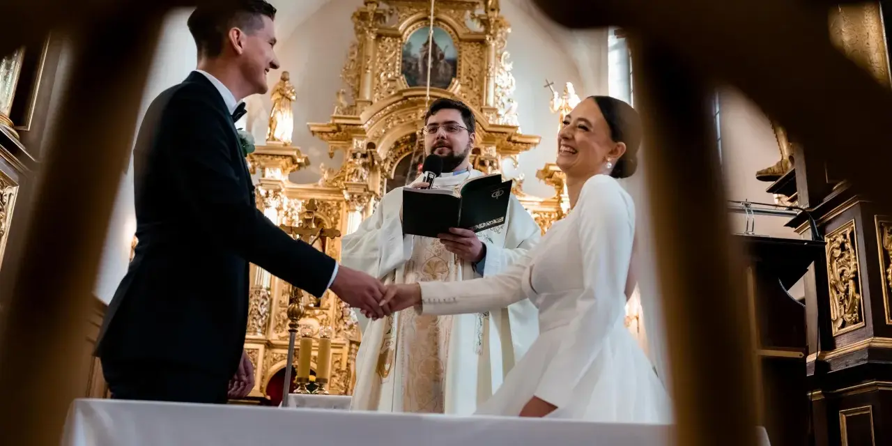 Para młoda ściska dłoń księdza podczas ceremonii. Zastanawiasz się, ile trwają nauki przedmałżeńskie?