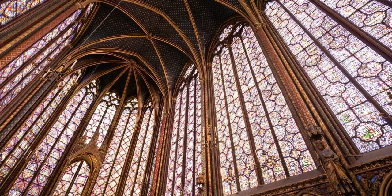 Interior de una capilla con vidrieras de colores y bóvedas ojivales, un ejemplo impresionante del estilo gótico.