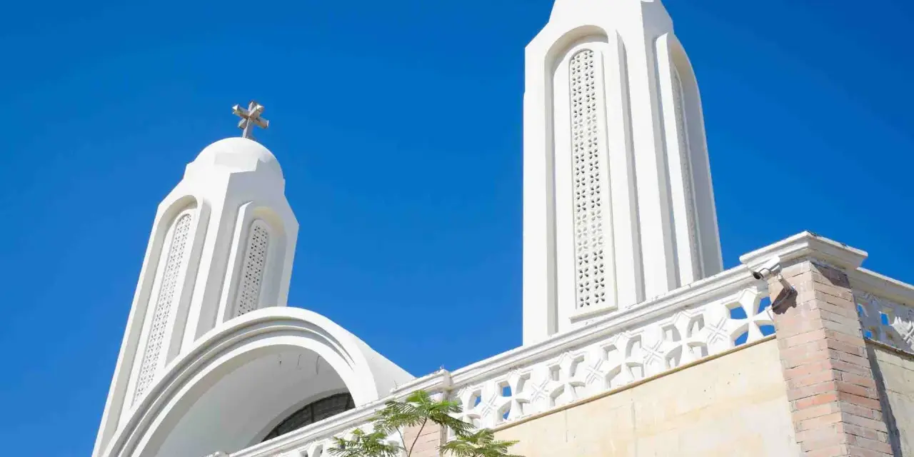 Białe wieże kościoła pod błękitnym niebem. Idealna pogoda w Egipcie w sierpniu, by podziwiać architekturę.