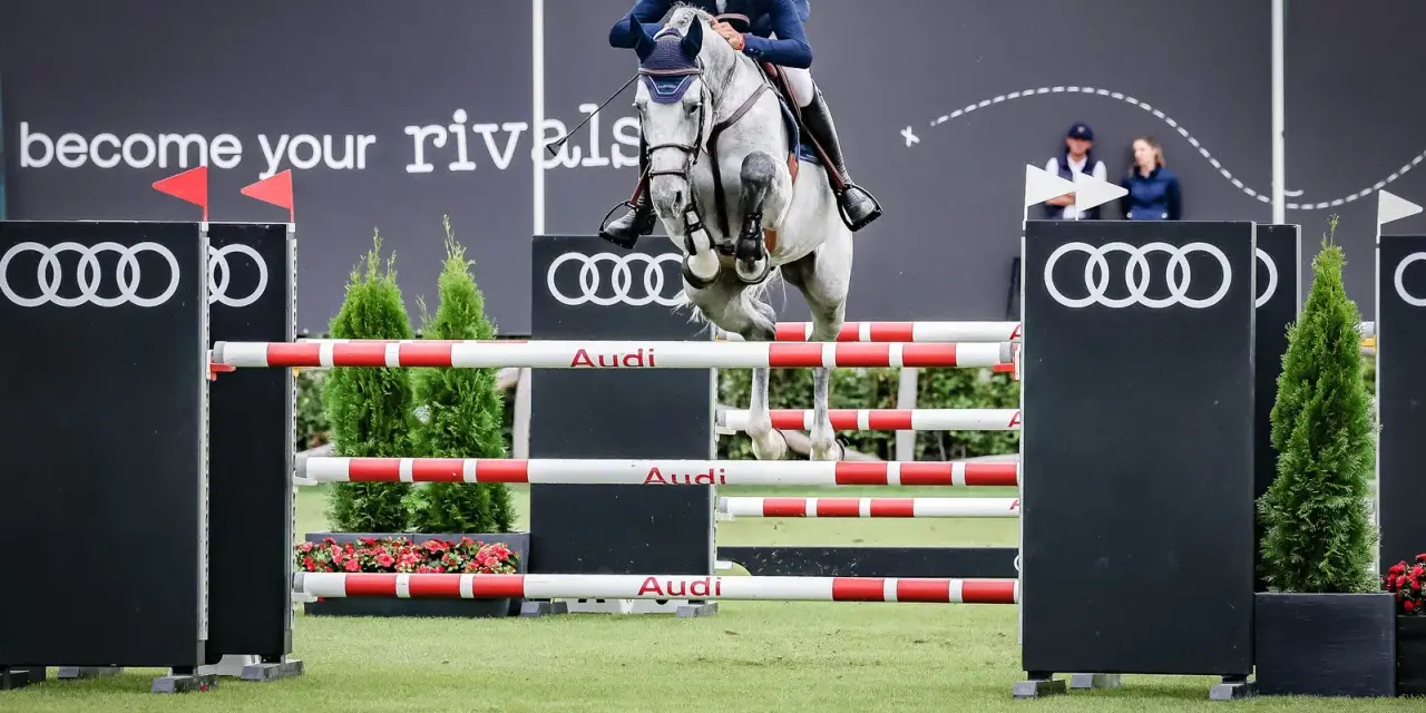 Un cavalier et son cheval gris s'envolent au-dessus d'une haie, défiant le fahrenheit de vains. Les logos Audi et le slogan "become your rivals" ornent le fond.