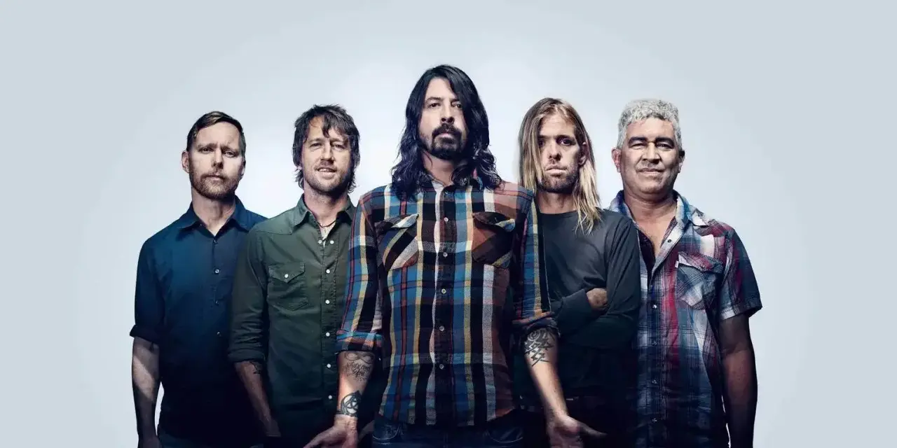 Les membres de Foo Fighters posent ensemble, cinq hommes aux regards intenses, prêts à enflammer la scène.