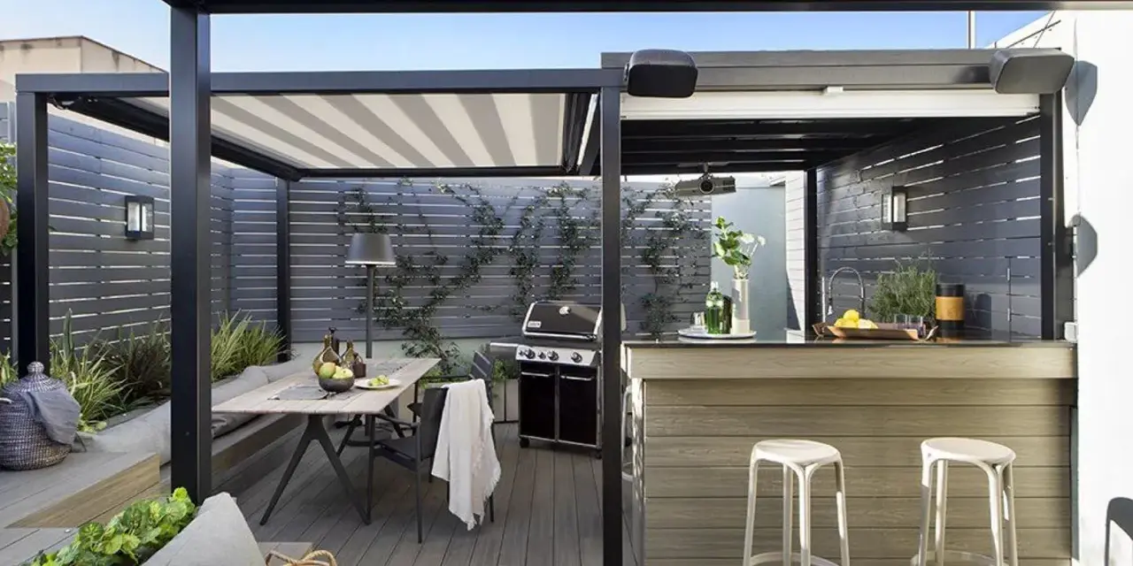 Porche moderno con mesa, parrilla y una barra de bar, ideal para disfrutar de una cocina exterior.