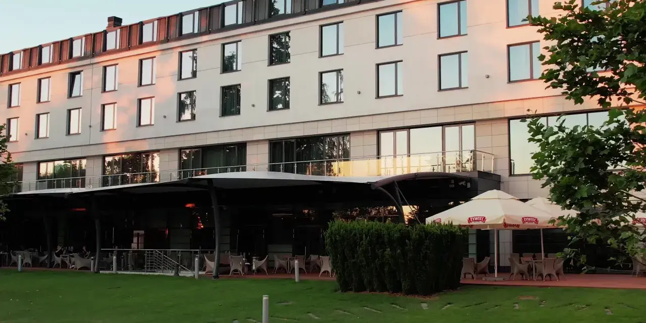 Nowoczesny hotel z tarasem i ogródkiem, gdzie można usiąść. Czy to jeden z hoteli Hilton w Warszawie?