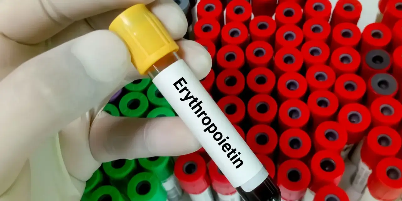 Ręka w rękawiczce trzyma probówkę z napisem "Erytropoetyna" na tle wielu innych probówek.