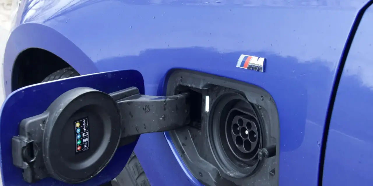 Niebieskie BMW 330e z otwartą klapką gniazda ładowania.