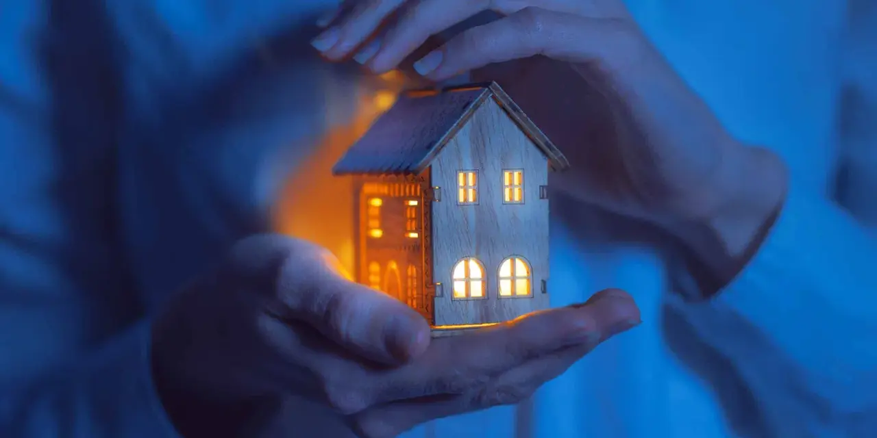 Mains tenant une maisonnette illuminée, symbolisant la jurisprudence logement de fonction et la protection du foyer.