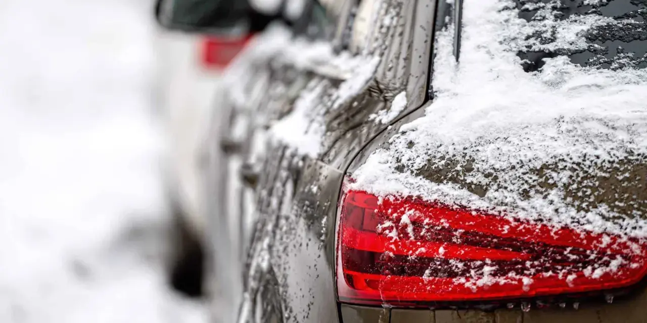 En mörk bil täckt av snö och is. En perfekt dag för ett bilvårdspaket för att få bilen skinande ren igen.