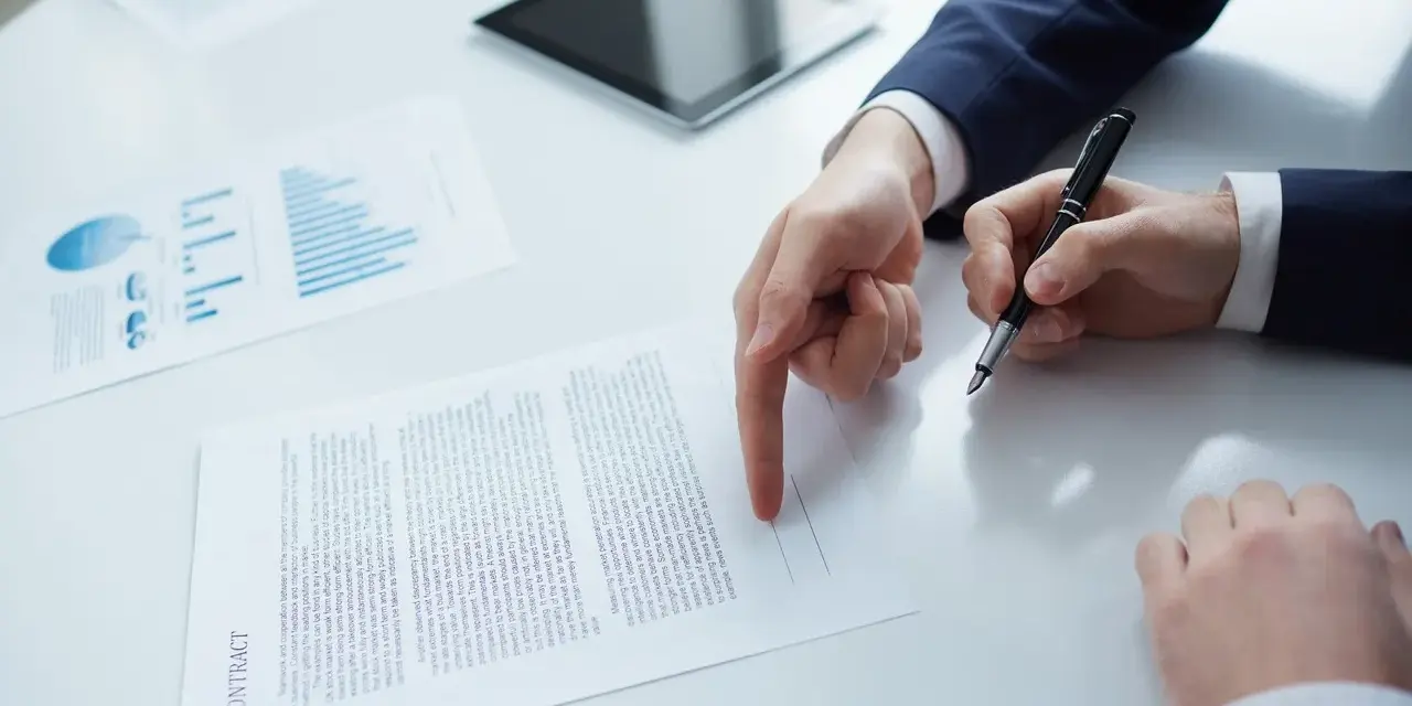 Biznesmen wskazuje palcem na dokument "CONTRACT", przygotowując się do podpisania umowy b2b.