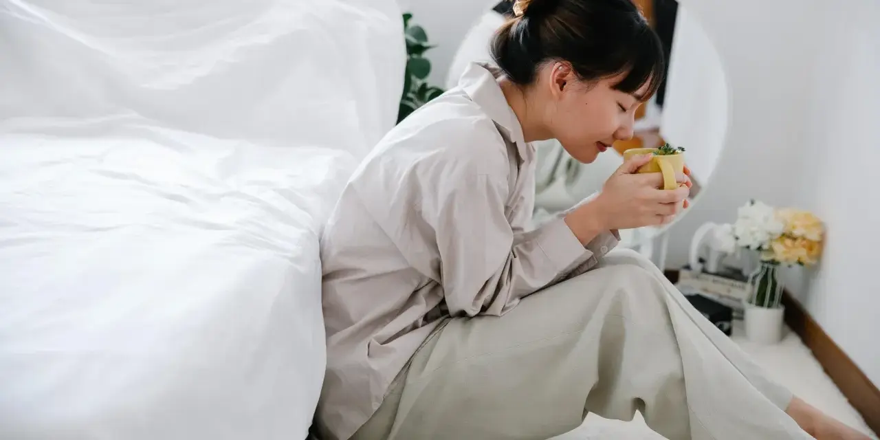 Mujer con taza de té, buscando remedios caseros para dormir de un tirón.