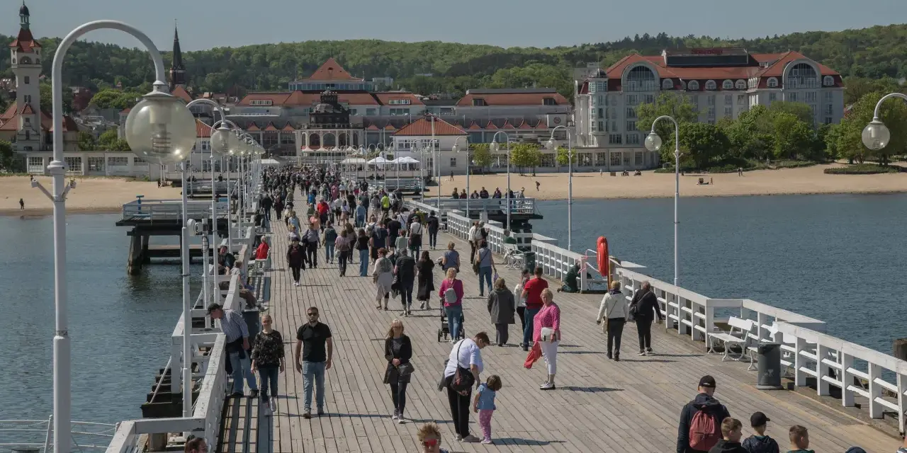 Spacer po molo w Sopocie, gdzie tłumy ludzi korzystają z uroków Bałtyku. To idealne miejsce na relaks i odkrywanie gdańskich atrakcji dla dorosłych.
