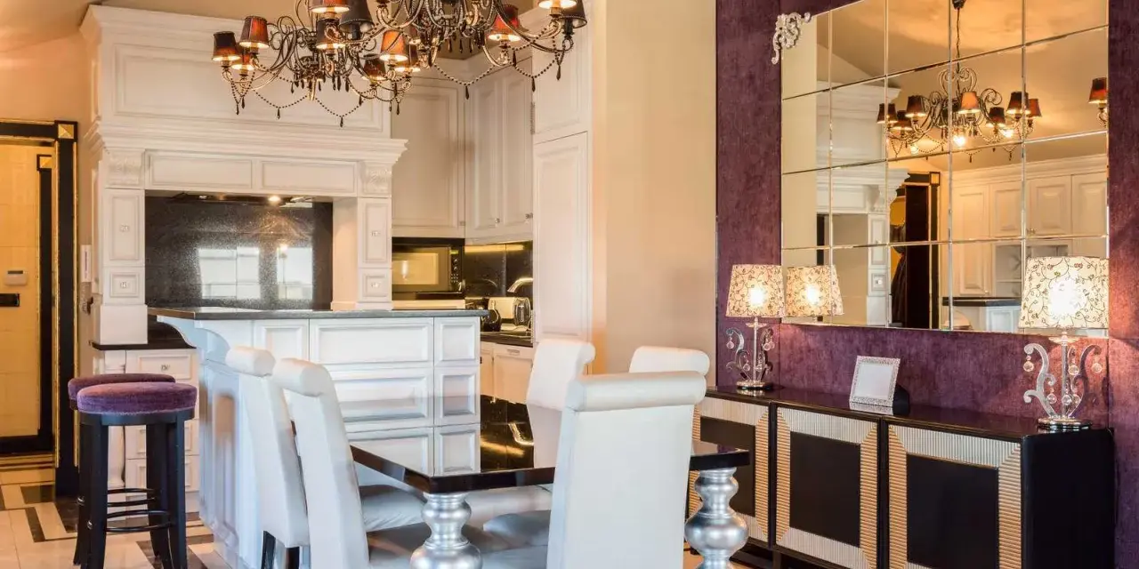 Elegancka jadalnia w stylu barokowym z bogato zdobionym żyrandolem, lustrami i fioletową tapetą.