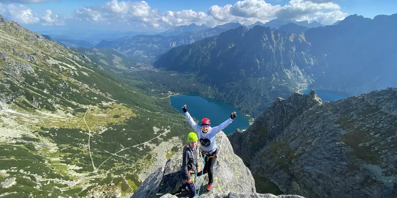 Dwóch wspinaczy na szczycie Mnich z widokiem na Tatry i Morskie Oko.
