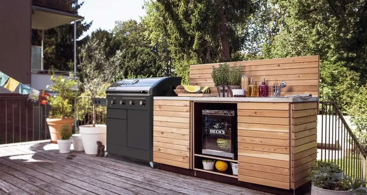 En hemmabyggd grill med diskbänk och kylskåp på en altan. Perfekt för sommarens grillfester!
