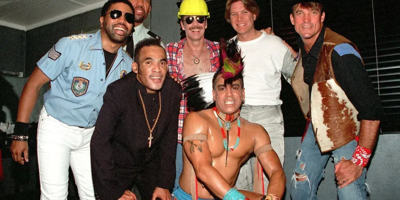 Groupe d'hommes costumés, certains rappelant des figures du disco. Qui a inventé le disco ? Difficile à dire avec ce joyeux groupe !