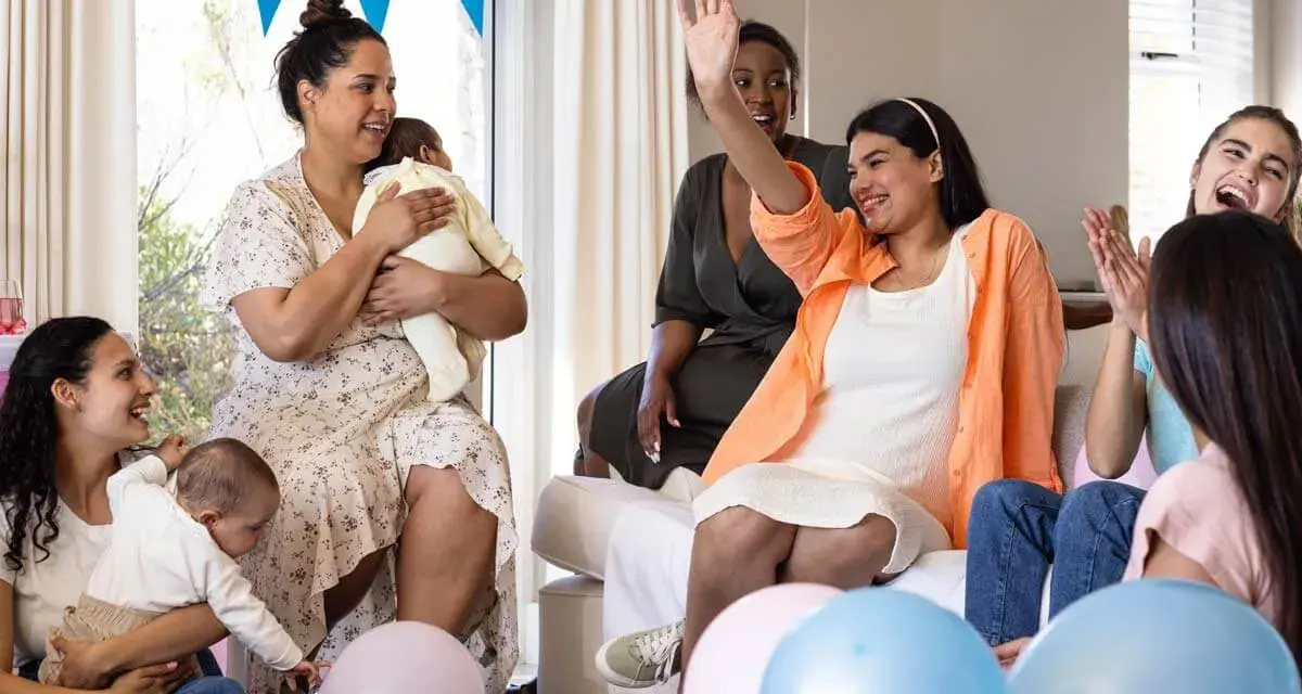 Glada kvinnor firar en babyshower med ballonger och bebisar. En kvinna vinkar glatt.