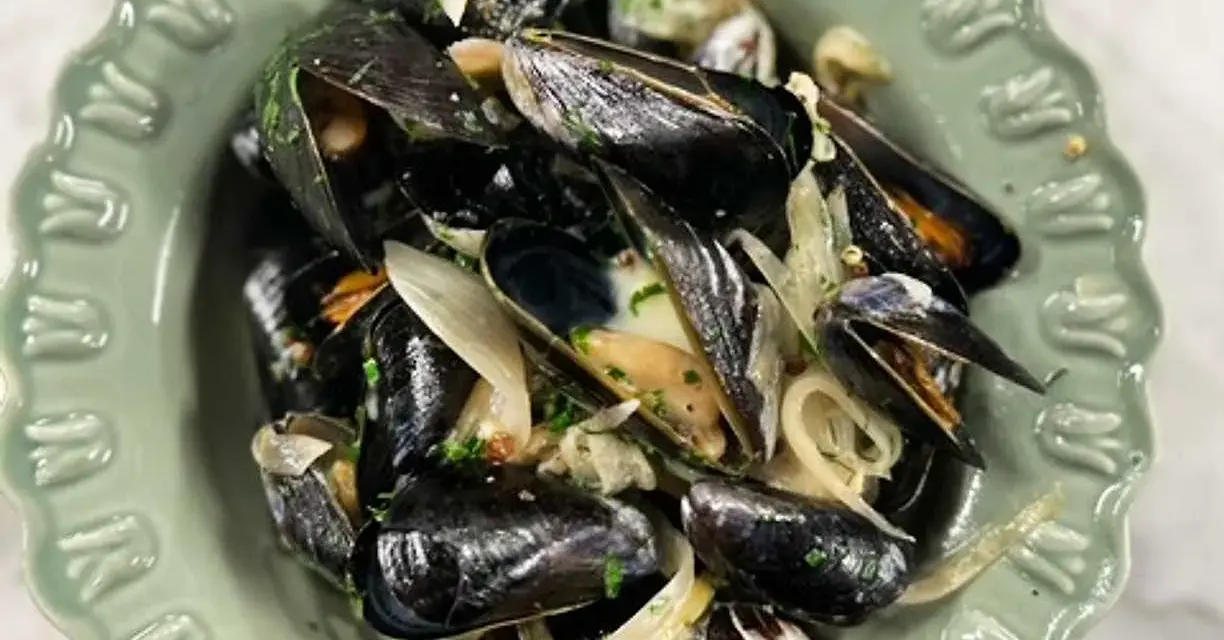 En skål med ångade musslor med lök och persilja. Ett enkelt och gott musslor recept.