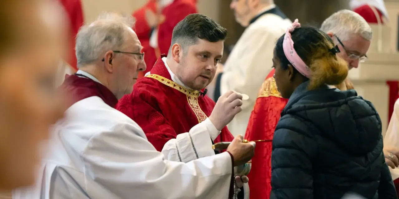 Clergy in red robes perform communion, a sacred act that can be seen as a form of evangelizing, sharing faith with a young woman.